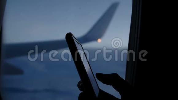 在飞机的窗户和机翼的背景上使用智能手机在晚上飞行视频的预览图