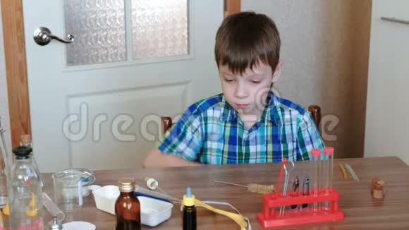 家庭化学实验男孩戴着安全黄色护目镜坐在桌子旁视频的预览图