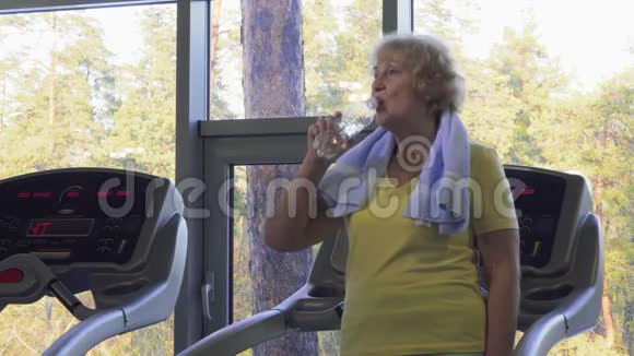 疲惫的老年妇女在健身房喝水视频的预览图