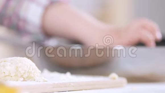 离焦的小女孩的手在厨房用面团雕刻出了干酪薄饼视频的预览图