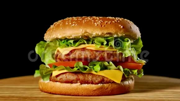 新鲜美味的汉堡在黑色背景上旋转无缝可循环射击4K视频的预览图