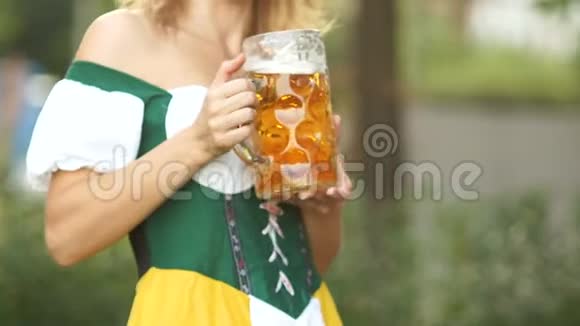 在一位身着国服的年轻女服务员手中特写一杯巴伐利亚啤酒音乐节视频的预览图