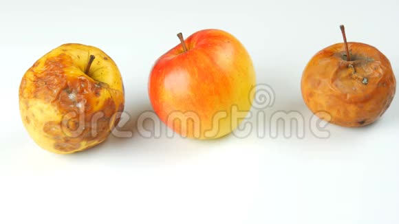 雌性手拿着成熟多汁和新鲜的苹果把成熟的腐烂变质的苹果放在白色的背景上视频的预览图
