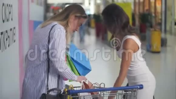 在超市附近有购物车的漂亮女人在卖东西视频的预览图