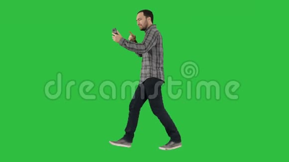 英俊的胡子男子录制vlog博客与智能手机同时走在绿色屏幕Chroma键视频的预览图