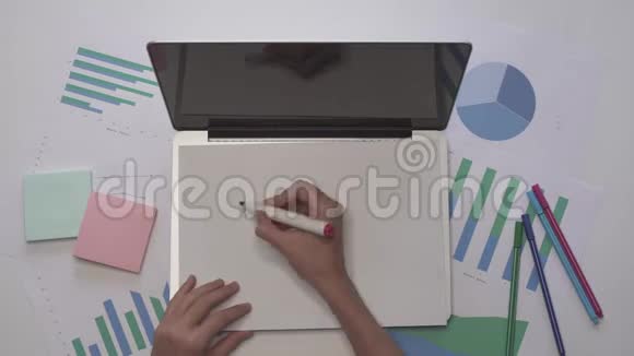 女人在笔记本电脑上的一张纸上写TEAMWORK带有图表的业务桌面视频的预览图