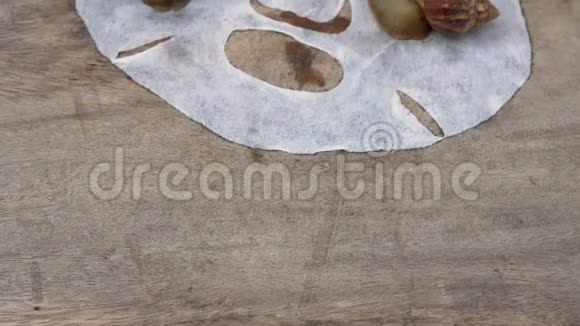 一组蜗牛在白色面具上的特写镜头脸在木制背景上拍摄蜗牛护肤治疗视频的预览图