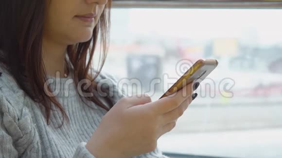 关闭年轻的黑发女人与电话大窗口背景视频的预览图