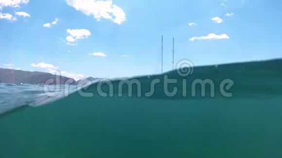 阳光明媚的一天海水中停泊着游艇的慢速水下镜头视频的预览图