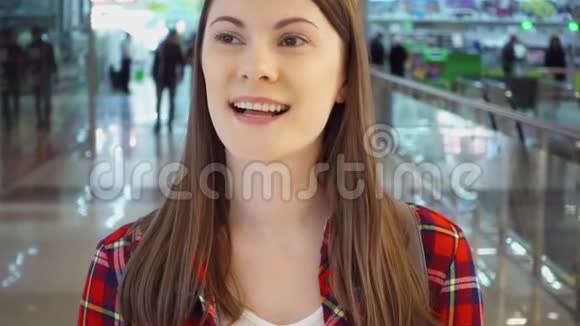 穿着红色衬衫的年轻女子微笑着在购物中心走来走去购物中心走廊的女顾客视频的预览图