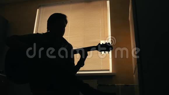 年轻有魅力的音乐家的黑色剪影用吉他戏剧和其他乐器作曲视频的预览图