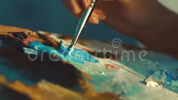 女艺术家手拿着不同颜料的脏调色板视频的预览图