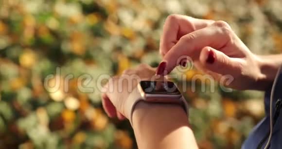 公园里的女跑步者一个女人在秋天的公园里工作时一边偷着她的智能手表休息视频的预览图