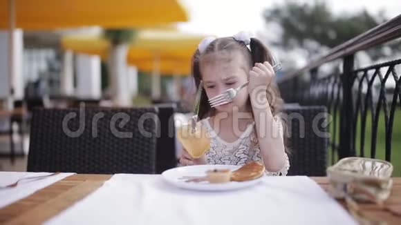 小女孩在街头咖啡馆里学着用刀叉吃饭视频的预览图