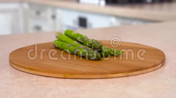盘子里装满了新鲜的绿芦笋旋转相机与白色厨房的背景多利射击视频的预览图