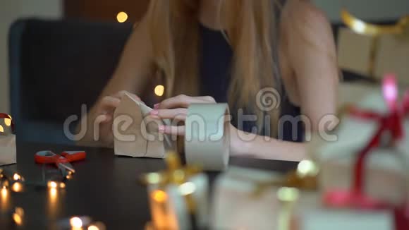 一个年轻女人的慢镜头正在包装礼物现在用工艺纸包裹着红色和金色的丝带视频的预览图