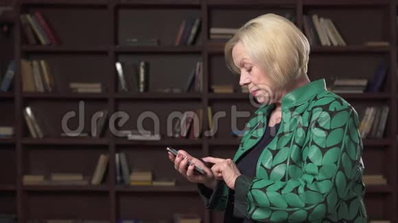 严肃的老年妇女在图书馆使用智能手机视频的预览图