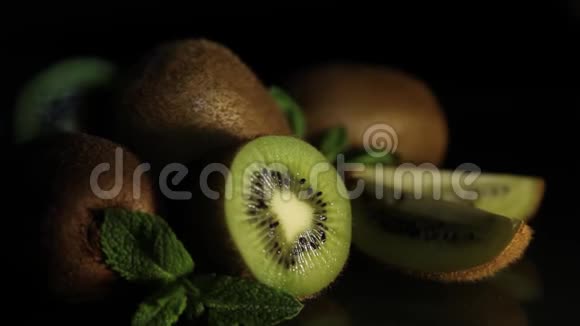 美味多汁的水果猕猴桃和薄荷放在黑桌上从桌子上反射猕猴桃几维鸟的碎片高清高清视频的预览图