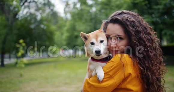 夏日公园里抱着漂亮小狗的快乐少女画像视频的预览图