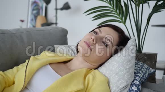 咳嗽生病的女人躺在家里的沙发上咳嗽视频的预览图