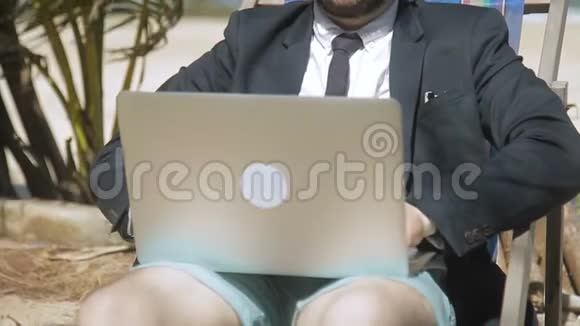 商人正在热带海滩用他的笔记本电脑写报告视频的预览图