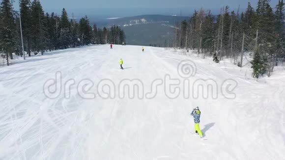 冬季人们在滑雪坡上的鸟瞰图开始从针叶林附近的跑道上下来景色令人惊叹视频的预览图