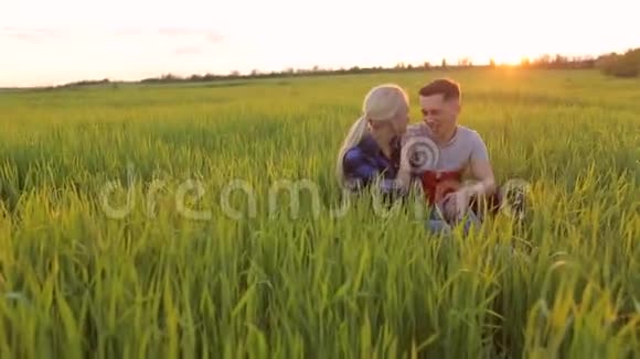 可爱的一对夫妇在日落时坐在麦田里视频的预览图