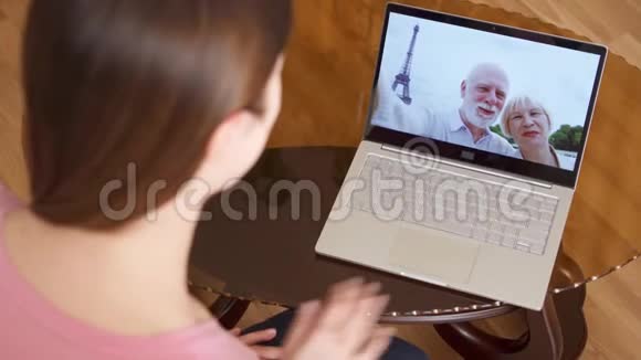 与法国巴黎的资深父母在笔记本电脑上通过信使应用程序进行视频聊天的女人视频的预览图