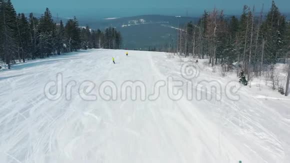冬季人们在滑雪坡上的鸟瞰图开始从针叶林附近的跑道上下来景色令人惊叹视频的预览图