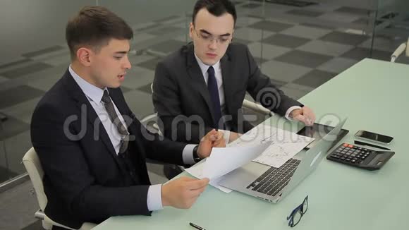 年轻的同事讨论文件坐在桌上手提电脑在公司视频的预览图