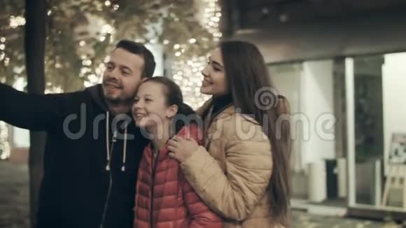 一个美丽的家庭晚上在城市街道上用灯光自拍视频的预览图