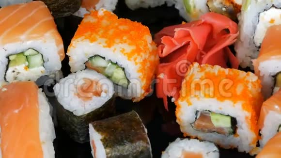 各种彩色寿司卷集和生姜旋转在镜面上的黑色背景日本料理视频的预览图