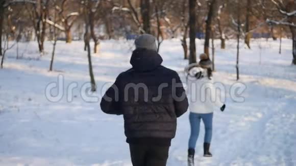 可爱的年轻夫妇在冬天的森林里奔跑视频的预览图