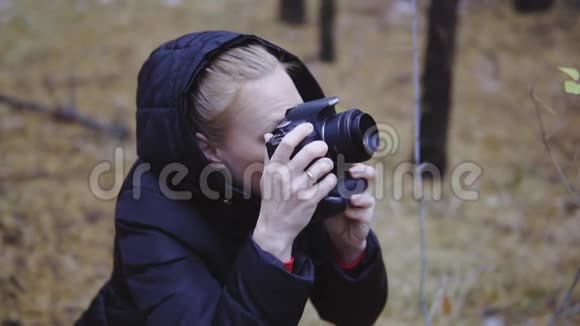 拿着相机的女孩为秋天的森林拍照深秋的第一场雪电影镜头慢动作视频的预览图