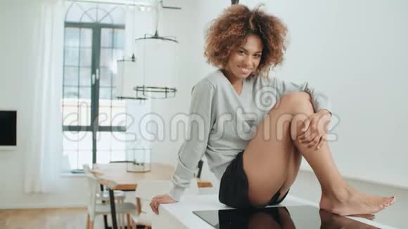 快乐年轻的非洲黑人妇女坐在家里的厨房桌子上视频的预览图