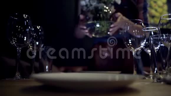 女人把花瓶放在桌子上行动女人的特写镜头把一瓶白色的花放在餐桌上视频的预览图