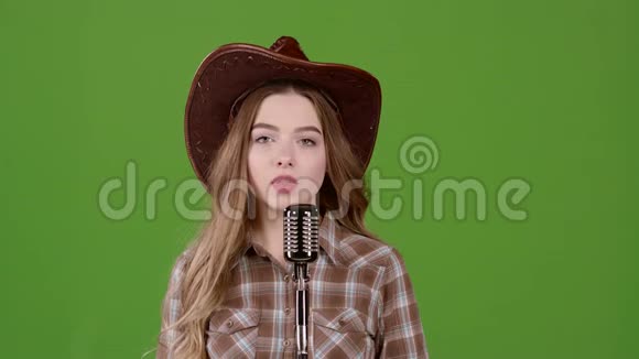 戴皮帽的牛仔女孩唱成复古麦克风绿色屏幕慢动作视频的预览图