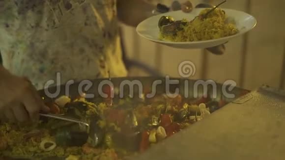 厨师用贻贝虾菖蒲和平底锅上的辣椒放热饭带着西班牙菜饭的男人视频的预览图