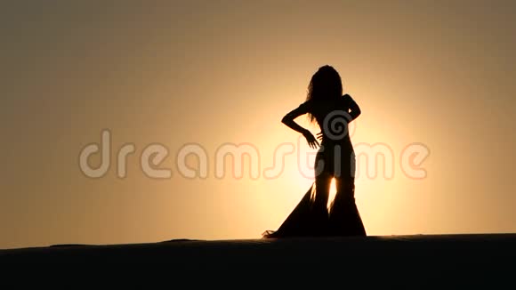 女孩可爱在日落背景下表演美丽的肚皮舞剪影视频的预览图