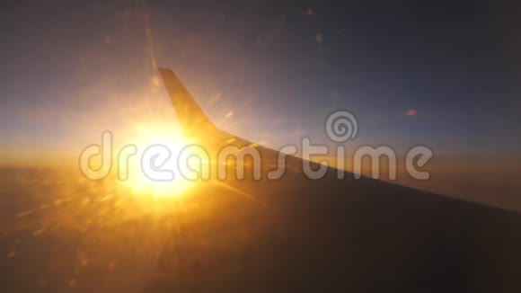 从飞机窗口到日出或日落用太阳的光飞行在云层之上的飞机翼飞机飞行视频的预览图