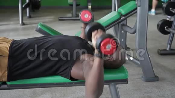 非洲男子在健身房做一个锻炼哑铃板凳压躺视频的预览图