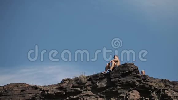 年轻人坐在悬崖边上视频的预览图
