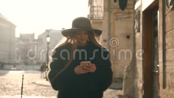 戴着灰色帽子和长发的年轻女子通过智能手机写短信视频的预览图