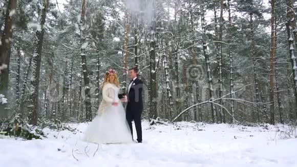 冬天的森林拍摄了一对年轻夫妇在下雪下玩得很开心慢动作视频的预览图