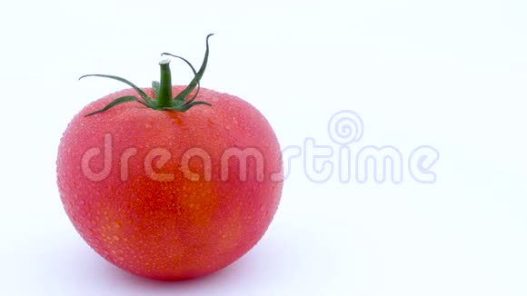 一整个红色的大番茄带水滴在转盘上慢慢旋转孤立在白色背景上左左视频的预览图