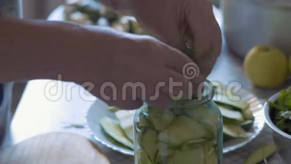 特写镜头一位老年妇女的双手将迪尔和欧芹的绿色材料放在一个装有白胡椒和黄瓜的玻璃罐子里视频的预览图