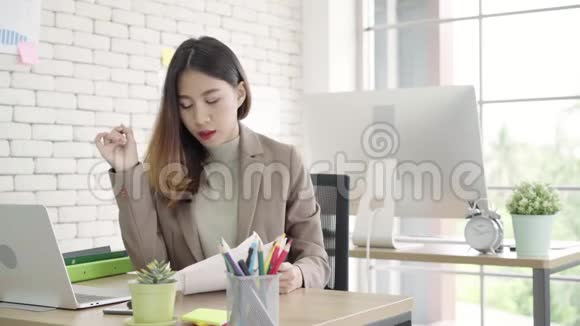 两位年轻的亚洲女商人在小企业的办公室里一起工作高兴地坐在那里阅读报告或文件视频的预览图