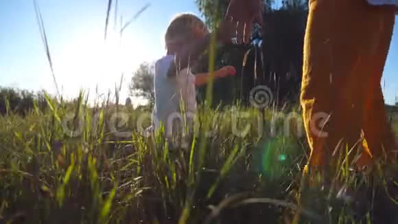 在一个阳光明媚的日子里年轻的父亲牵着他的孩子把他扔到草地上爸爸和儿子玩视频的预览图