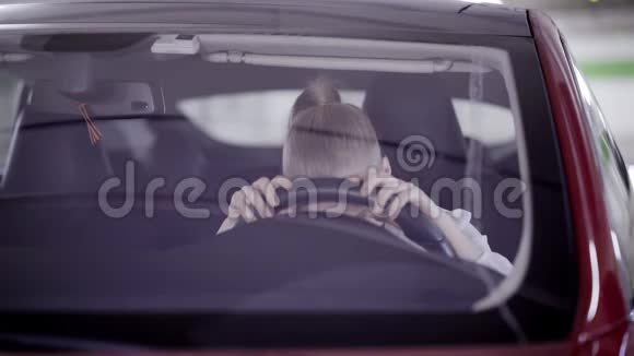 带马尾辫的绝望女人坐在红色的车上把头放在方向盘上视频的预览图