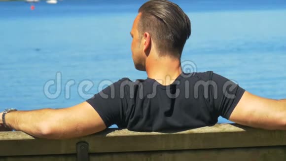 一个人在美丽的湖前的长凳上享受着美好的天气视频的预览图